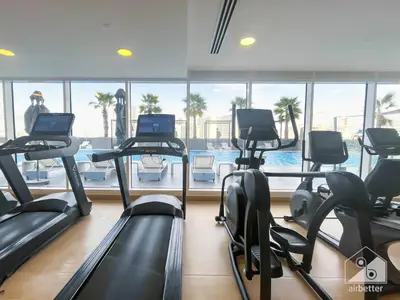 a gym with cardio machines and a swimming pool at Stunning 1B With Balcony & City Views - Dubai in Dubai