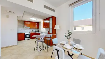 a kitchen and living room with a table and chairs at Widcombe House - Tranquil One Bed in Motor City in Dubai