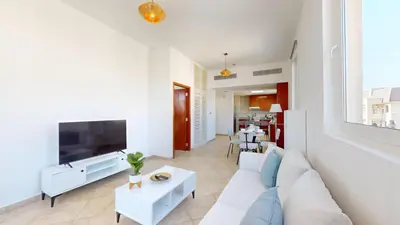 a living room with a white couch and a tv at Widcombe House - Tranquil One Bed in Motor City in Dubai