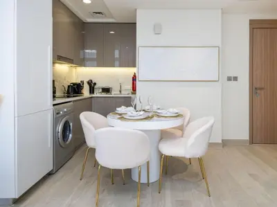 a kitchen with a white table and white chairs at Serene 1-Bedroom Retreat in Azizi Riviera with Calming Tones in Dubai