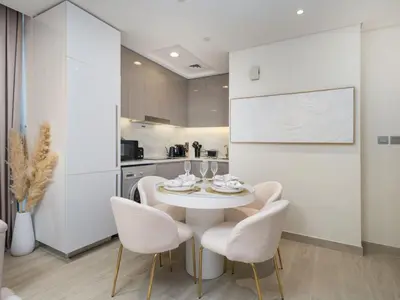 a white dining room with a white table and chairs at Serene 1-Bedroom Retreat in Azizi Riviera with Calming Tones in Dubai