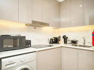 a white kitchen with a microwave and a dishwasher at Serene 1-Bedroom Retreat in Azizi Riviera with Calming Tones in Dubai