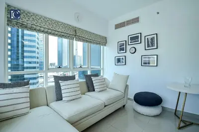 a living room with a white couch and a large window at Cozy 1-Bedroom Apartment in N2 Lakepoint Tower JLT in Dubai