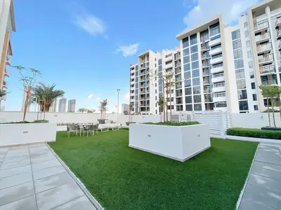a courtyard with grass and white buildings at Brand New Spacious 3-BedroomIAzizi Riviera 16 in Dubai