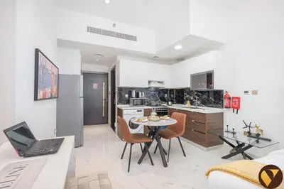 a kitchen with a table with a laptop on it at Vogue Arjan Jwelz by Danube near Miracle and Butterfly Garden, Studio Apartment with Balcony and Vibrant Community View, Access to all Amenities in Dubai