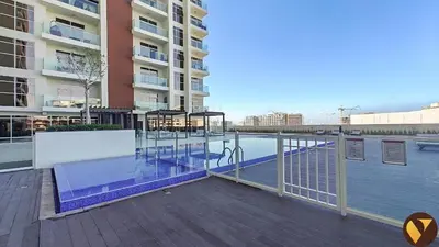 a balcony with a swimming pool next to a building at Vogue Arjan Jwelz by Danube near Miracle and Butterfly Garden, Studio Apartment with Balcony and Vibrant Community View, Access to all Amenities in Dubai