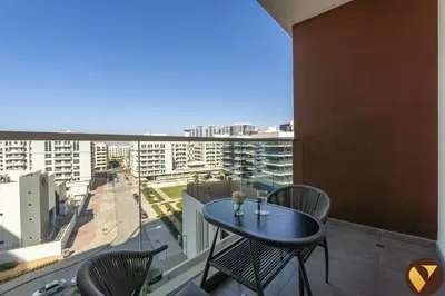 a table and chairs on a balcony with a view of a city at Vogue Arjan Jwelz by Danube near Miracle and Butterfly Garden, Studio Apartment with Balcony and Vibrant Community View, Access to all Amenities in Dubai