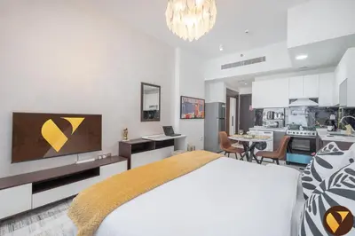a white bedroom with a large bed and a kitchen at Vogue Arjan Jwelz by Danube near Miracle and Butterfly Garden, Studio Apartment with Balcony and Vibrant Community View, Access to all Amenities in Dubai