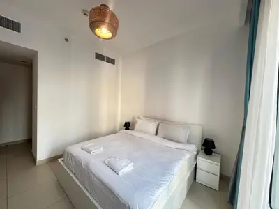 a white bedroom with a bed with white sheets and pillows at Coastal Charm - Fully Furnished 2-Bedroom Apartment with Spectacular Views by Petals Holiday Homes in Dubai