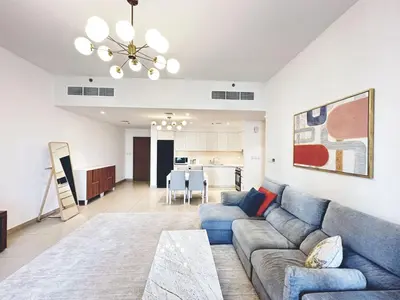 a living room with a blue couch and a kitchen at Coastal Charm - Fully Furnished 2-Bedroom Apartment with Spectacular Views by Petals Holiday Homes in Dubai
