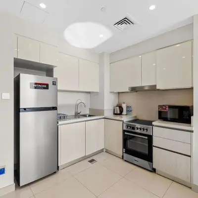 a kitchen with white cabinets and a stainless steel refrigerator at Park Point C-1 bedroom for monthly stay-1005 in Dubai