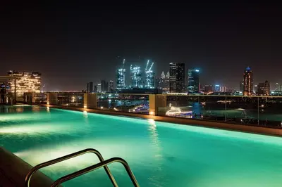 a swimming pool with a city skyline at night at Seaside Serenity 1Bd Beachfront Apartment in Dubai