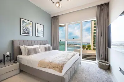 a bedroom with a large bed and a large window at Seaside Serenity 1Bd Beachfront Apartment in Dubai