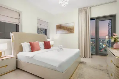 a white bedroom with a large bed and a window at Elegant 2BR with Balcony and Burj Khalifa Skyline Views in Dubai