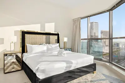 a bedroom with a large bed with a large window at Elegant 2BR with Balcony and Burj Khalifa Skyline Views in Dubai
