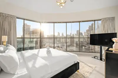 a bedroom with a large white bed and a large window at Elegant 2BR with Balcony and Burj Khalifa Skyline Views in Dubai