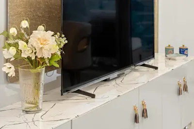 a vase of flowers on a counter with a television at Elegant 2BR with Balcony and Burj Khalifa Skyline Views in Dubai