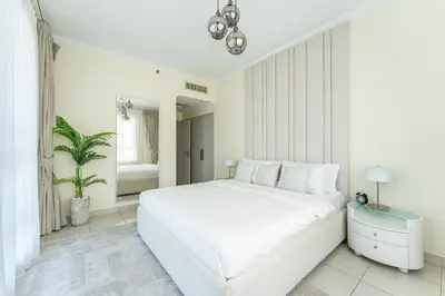 a white bedroom with a white bed and a plant at HAVN - 2 Bedroom in Marina Quays, Dubai Marina in Dubai