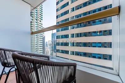 a balcony with two chairs and a large building at Revamped 1BR Unit with Partial Sea & Palm Jumeirah Views Close to Beach , Elite Residence, Dubai Marina by Deluxe Holiday Homes in Dubai