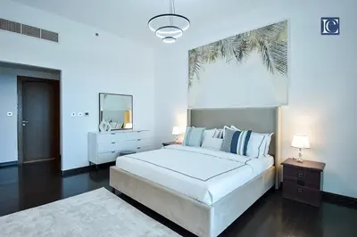 a white bedroom with a large bed and a mirror at Exclusive 2BR Home Marina Residence 4, The Palm in Dubai