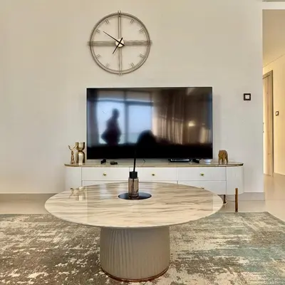 a living room with a table and a large clock at THE COVE Creek Harbour in Dubai