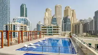 a rooftop pool with white chairs and a city skyline at Spacious High Floor Apartment Dubai Marina in Dubai