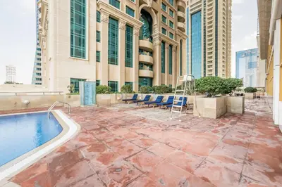 a patio with a pool and chairs and a building at Upgraded 1BR Overlooking Palm Jumeirah & Sea Views from Living to Bedroom, Elite Residence, Dubai Marina by Deluxe Holiday Homes in Dubai