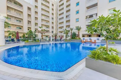 a large swimming pool in front of a building at Waves - Spacious 1BR with Balcony & Cozy Interiors in JVC in Dubai