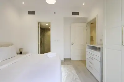 a white room with a bed and a kitchen at Livbnb-Modern 1BR Oasis with Stunning Terrace, JVC in Dubai