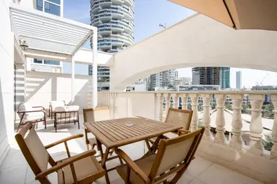 a table and chairs on a balcony with a view at Livbnb-Modern 1BR Oasis with Stunning Terrace, JVC in Dubai