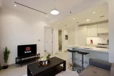 a kitchen and a living room with a couch and a table at Livbnb-Modern 1BR Oasis with Stunning Terrace, JVC in Dubai