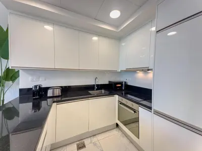 a kitchen with white cabinets and a sink at Luxury Meets Serenity 2BR Apt in Noura Tower in Dubai