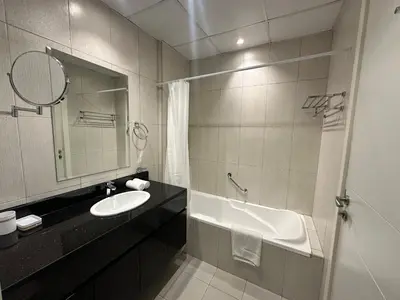 a bathroom with a sink and a tub and a mirror at Stunning Studio at JVC Damac Ghalia - Msgetaways in Dubai