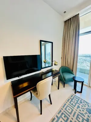 a living room with a piano and a green chair at Stunning Studio at JVC Damac Ghalia - Msgetaways in Dubai