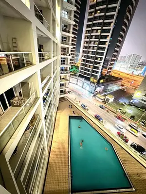 a building with a pool in the middle of a city at Bed in mixed room in Dubai