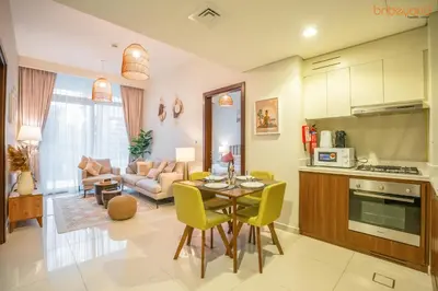a kitchen and living room with a table and chairs at Cozy Retreat with Burj Views by Bnbeyond in Dubai