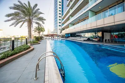 a swimming pool in front of a building with a palm tree at 160M2 Modern 2-bedrooms apartment with fantastic views in Dubai