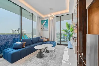a living room with a blue couch and a table at FAM Living - Samana Park Views - Brandnew 1Bed in Dubai