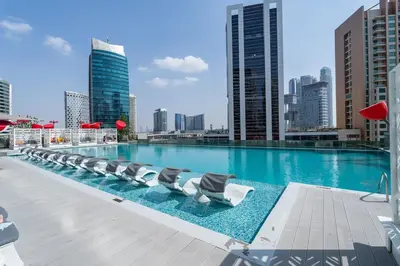a large swimming pool with lounge chairs on a building at Vogue Downtown Mag 318 near Burj Khalifa and Dubai Mall, Studio Apartment with Balcony, Canal and City View, Access to all Amenities in Dubai
