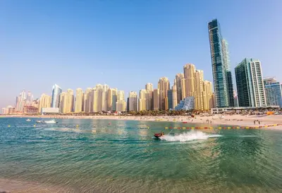 a boat in the water in front of a city at Cozy 1bd near JBR Beach in Dubai