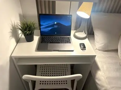 a laptop computer sitting on a desk next to a bed at Elegance Partition Room in Tecom Near ICM Metro in Dubai