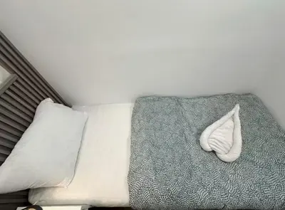 a white sock sitting on a bed with pillows at Elegance Partition Room in Tecom Near ICM Metro in Dubai