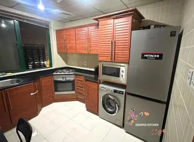 a kitchen with wooden cabinets and a refrigerator at Center Point Partition Room in Tecom in Dubai