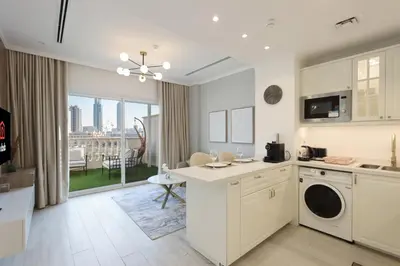 a kitchen with white cabinets and a large window at Livbnb - Homey 1B with Spacious Terrace in District 14, JVC in Dubai