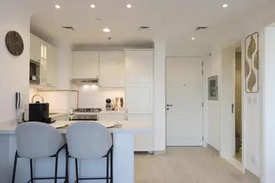 a kitchen with white cabinets and a counter with stools at Livbnb - Homey 1B with Spacious Terrace in District 14, JVC in Dubai