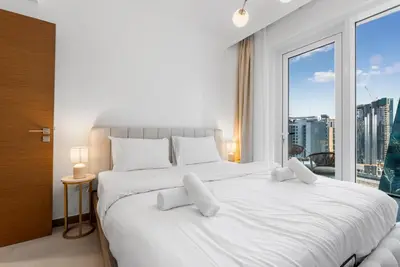 a bedroom with a large white bed with a large window at LUX 2BR in Missoni Tower - 5 mins to Burj Khalifa in Dubai