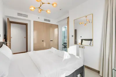 a bedroom with a large white bed and a mirror at LUX 2BR in Missoni Tower - 5 mins to Burj Khalifa in Dubai