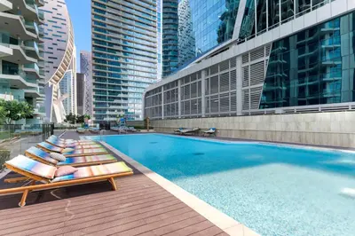 a swimming pool with chaise lounges and chairs next to buildings at LUX 2BR in Missoni Tower - 5 mins to Burj Khalifa in Dubai