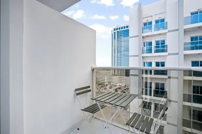a balcony with two chairs and a building at Newly Built Studio - Urban Living in Dubai