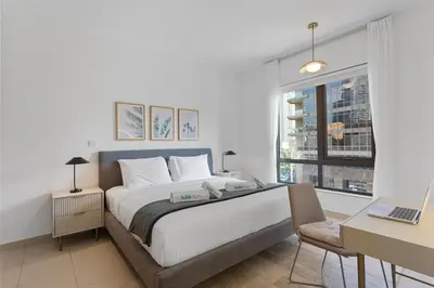 a bedroom with a bed and a desk and a window at Exquisite centrally located 1BR in Downtown Dubai in Dubai